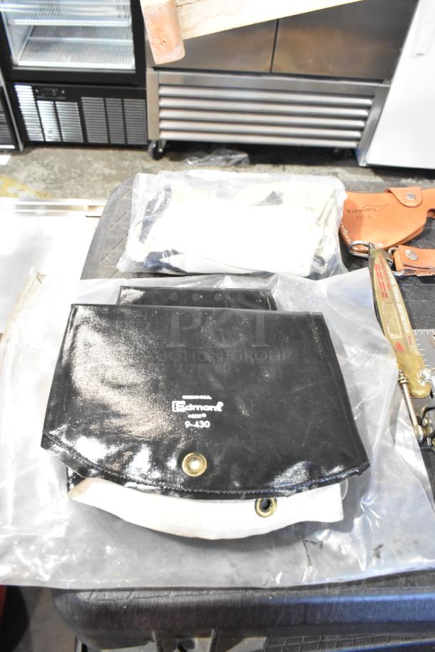 Two various bags including a black Edmoné 9-430 bag, leather Estwing No. 8 sheath, and tools like trowels visible.