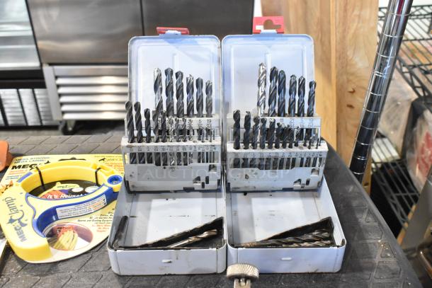 Two cases of assorted drill bits organized by size, and a Mega Clamp cable clamp. Items in good condition.