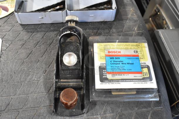 Boxed Bosch WB 569 4" crimped wire wheel and an old handheld plane on a textured surface.