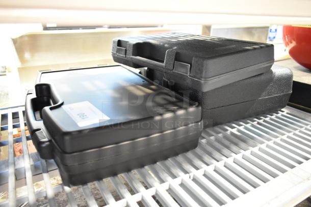 Three hard black cases containing tools, stacked on a shelf. Each case appears in good condition, labeled with "Lot 190."