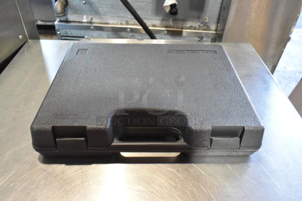 Hard black carrying case with secure latches, textured surface, labeled "Made in Taiwan," contains various tools.