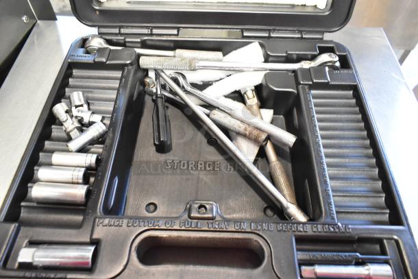 Black tool case containing various tools, including socket wrenches and drivers. Labeled "Storage Area." Good condition.