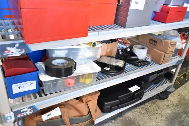 Tiered shelf with various items including red bins, duct tape, sealed poly bins, and cardboard boxes. Auction tags visible.