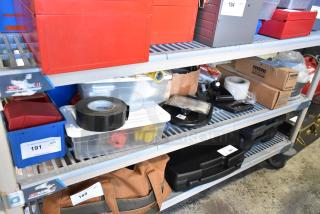Tiered shelf with various items including red bins, duct tape, sealed poly bins, and cardboard boxes. Auction tags visible.