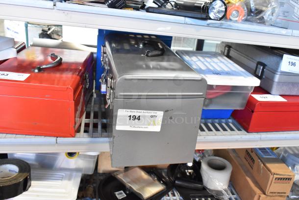 Two metal toolboxes, one red and one gray, with contents including a Skilsaw saw, labeled for auction, in used condition.