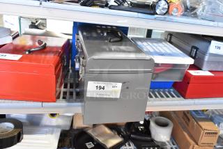 Two metal toolboxes, one red and one gray, with contents including a Skilsaw saw, labeled for auction, in used condition.