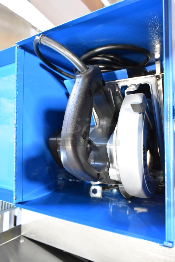 Blue metal toolbox containing a Skilsaw saw, visible handle and cord, appears in good condition, part of auction lot.