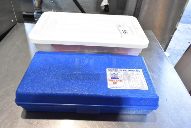 Two poly bins with contents, including a Lenox Super Electrician Hole Saw Kit in blue case, placed on metal surface.