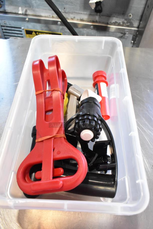 Clear poly bin containing a red hole saw kit and various tools. Items are secured with a rubber band, showing signs of light use.