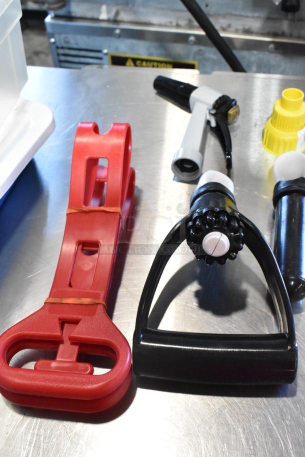 2 various poly bins with contents including a hole saw kit, plastic nozzles, and a red plastic holder on a metal surface.