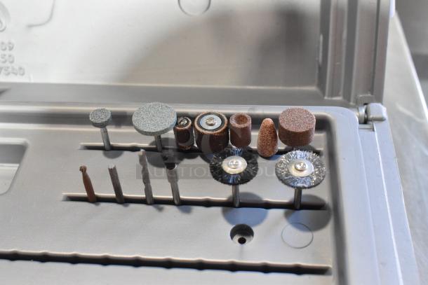 Dremel MultiPro variable speed electric drill in gray case with various accessories including grinding and polishing bits.