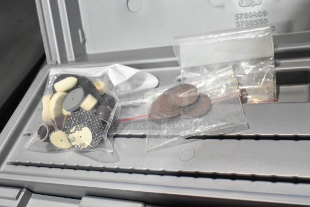 Dremel MultiPro electric drill accessories in a gray case, featuring multiple sanding and polishing attachments in clear bags.