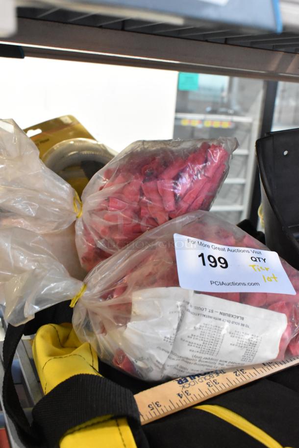 Tier lot of various items including a glue gun kit, flashlight, and worklight. Bag labeled with auction info and lot number 199.