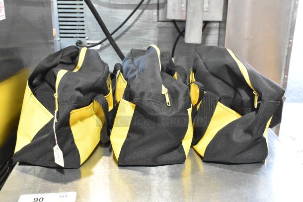 Three black and yellow bags containing a dusting brush and kneepads, displayed on a metal surface.