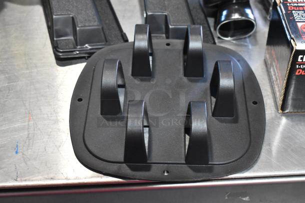 A black kneepad component on a metal surface, part of a set with dusting brush and other contents.