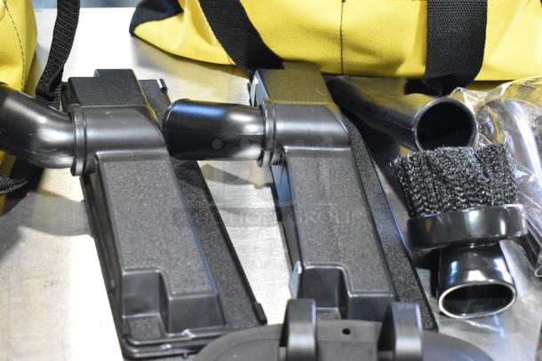 Three black and yellow bags with contents including a dusting brush and kneepads, shown on a metal surface.