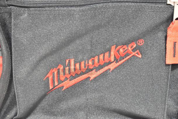 Milwaukee soft tool bag with branded red logo, black fabric, visible zipper; ideal for tool storage, in good condition.