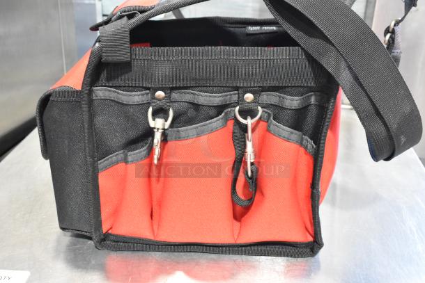 Milwaukee soft tool bag, red and black, with multiple exterior pockets and clip attachments. Appears in good condition.