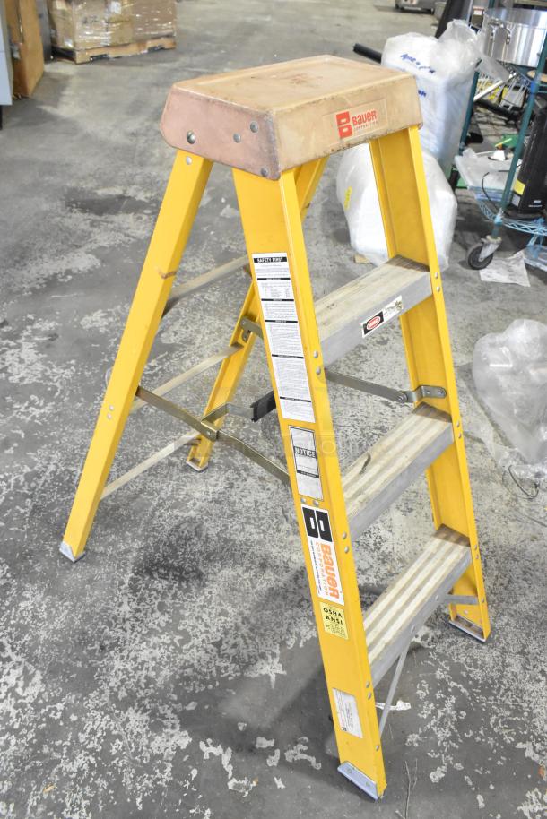 Bauer A-frame ladder, 300 lb capacity, yellow, sturdy metal steps, safety labels visible, used condition.