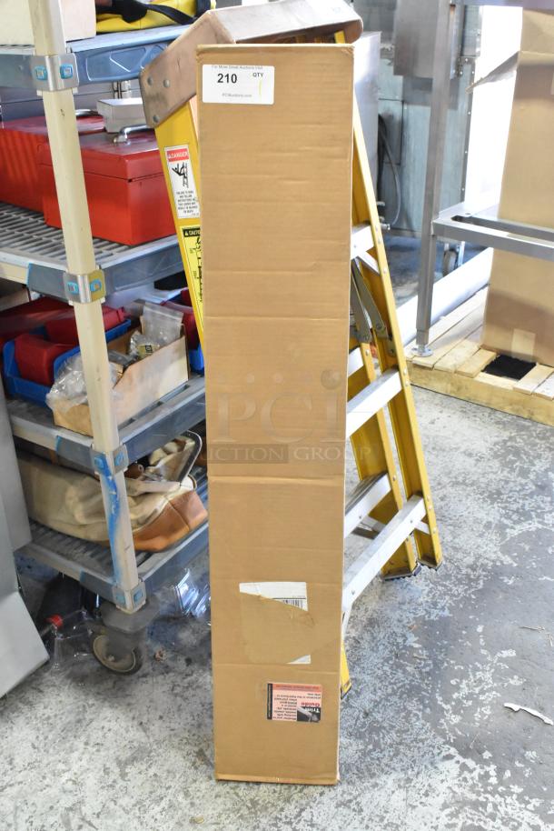 Cardboard box labeled "Trim Guide," in good condition, placed beside a ladder in a storage area, auction lot 210.