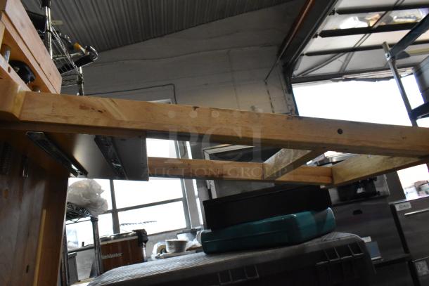 Wooden table with visible natural grain and sturdy frame. Showcasing construction details; ideal for workshops. Some wear evident.