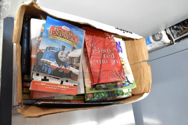Box of mixed items, including books like "Holiday Express" and "Low Red Moon," in fair condition. Other assorted titles visible.