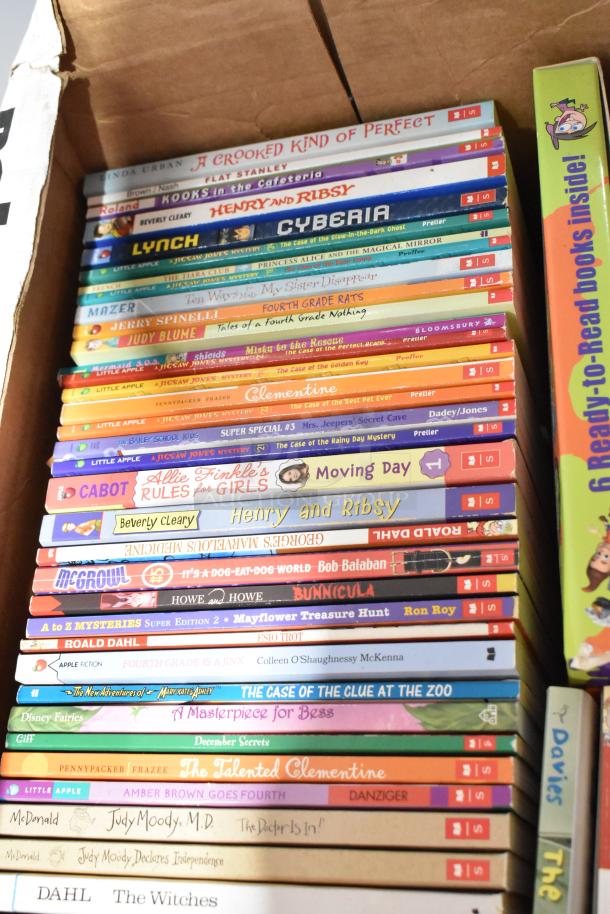 Tiered lot of children's books in a cardboard box. Includes titles like "A Crooked Kind of Perfect," "Flat Stanley," and "Henry and Ribsy."
