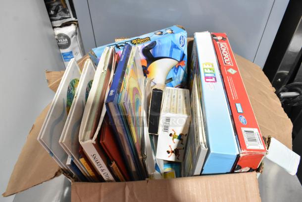Box of assorted items including board games, books, and a Vornado fan. Various conditions. Games include Monopoly and The Game of Life.