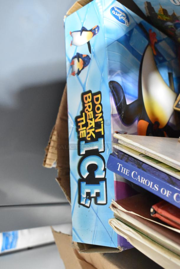 Box of various items including "Don't Break the Ice" game and books, part of an auction tier lot.