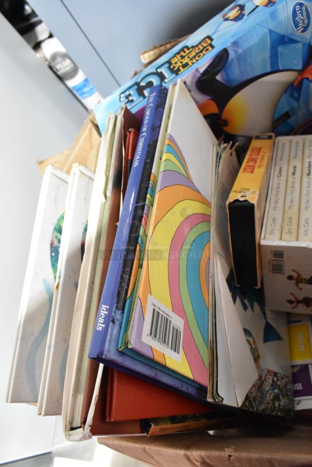 Tier lot of assorted items including a Vornado fan box, colorful books, and a "Don't Break the Ice" game, in used condition.