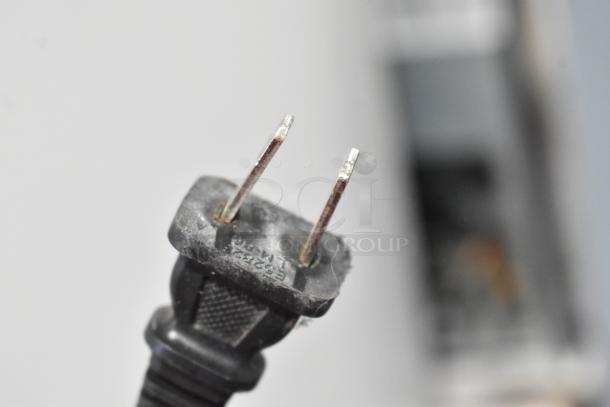 Close-up of a two-prong electrical plug with visible wear, showing minor scratches and slight corrosion on the pins.