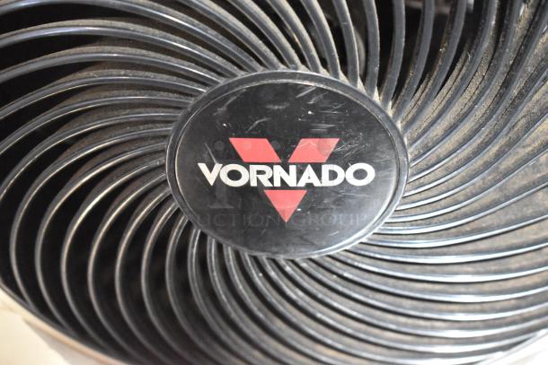 Vornado fan close-up, showing logo on front grille. Part of a mixed auction lot with books. 