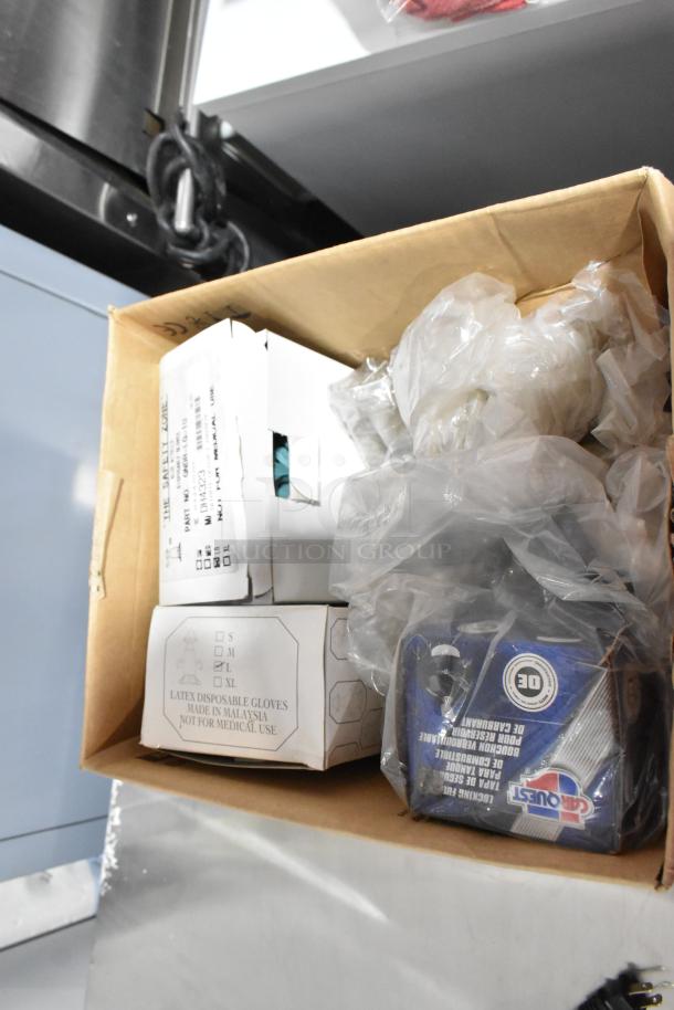 Cardboard box with various items including latex gloves marked "L," books, and a Vornado fan, all in used condition.