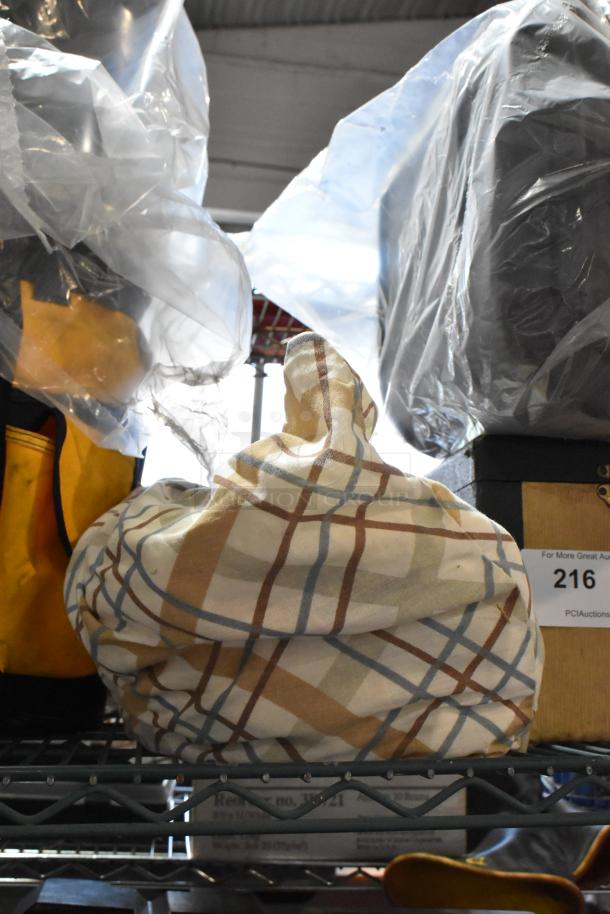Tiered lot of assorted items including a wrapped tool bag with a plaid cloth on a metal shelf. Auction label "216" visible.
