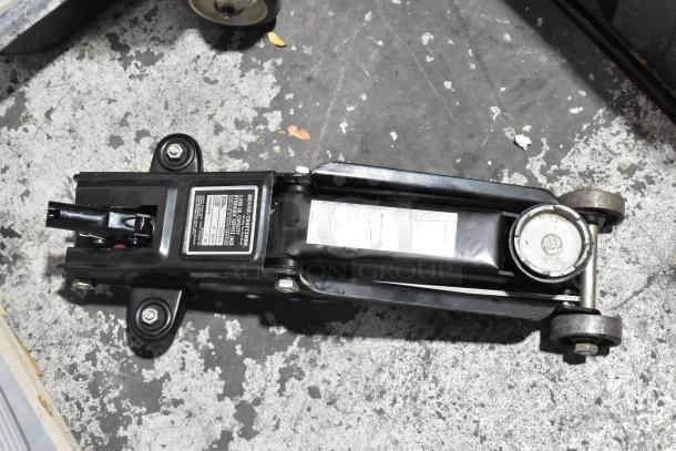 Craftsman 5,000 lb Capacity Hydraulic Service Jack on concrete floor. Visible label indicates model and specs.