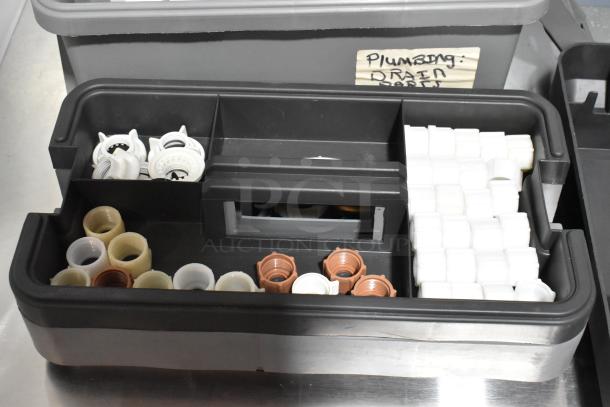Three gray poly tool boxes filled with assorted plumbing components. Label reads "Plumbing Drain Parts." Auction includes contents.