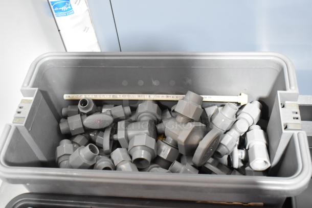 Three gray poly toolboxes containing assorted plumbing fittings and connectors, shown with visible QEST brand markings.