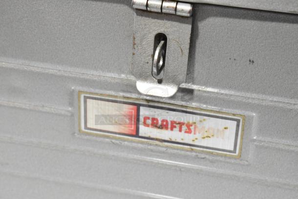 Craftsman gray metal tool box, visible latch and label, slight rust. Durable construction, ideal for tool storage.
