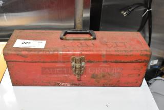 Red metal tool box with contents, visible wear and rust, black handle, latch closure, auction tag numbered 223.