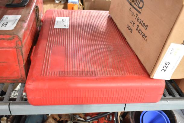 Red hard case containing Deluxe Air Compressor, sturdy design, labeled "224," in good condition on metal shelf.
