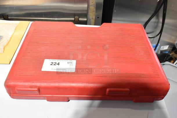 Red hard case for Deluxe Air Compressor, marked with auction label "224." Case shows light wear, secure latches.