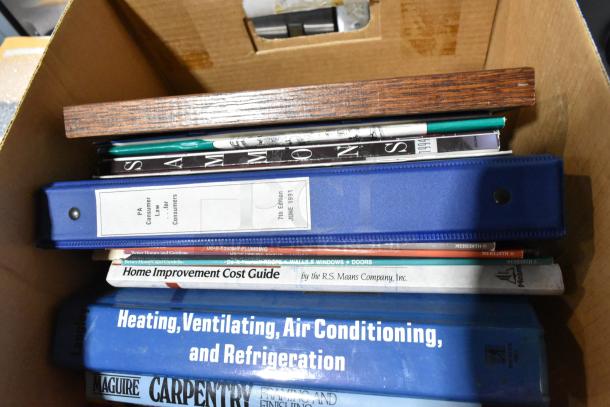 Cardboard box with assorted books and binders, including home improvement guides and a PA consumer law guide, indicating mixed lot.