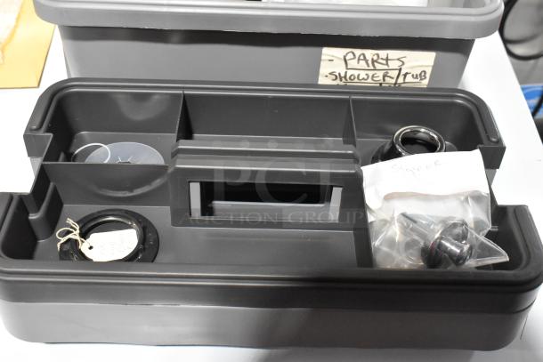 Gray tool box with compartments containing shower/tub parts and stoppers. Labeled for organization. In good condition.