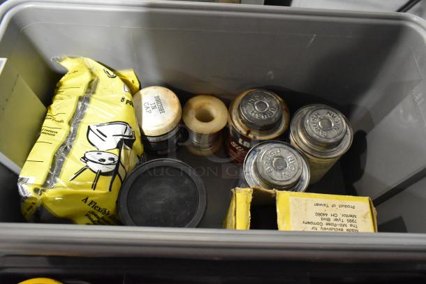 Gray toolbox containing various items including a yellow bag, metal containers with "Brush Cap," and coiled wire, showing used condition.
