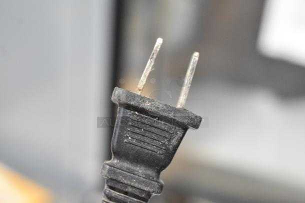 Close-up of a plug for a Pelonis HQ-1000B Quartz Heater, 120 Volts, 1 Phase. Black color, showing signs of wear.