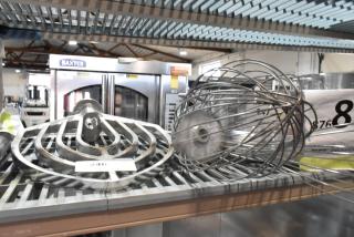 Three new scratch and dent attachments: paddle, whisk, and long-handled whisk on metal rack, auction setting.