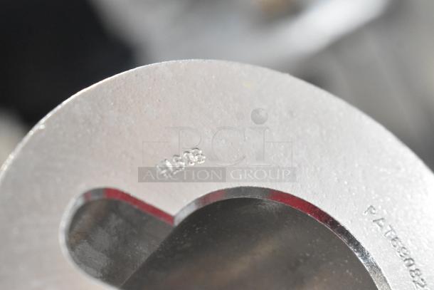 Close-up of a metallic kitchen attachment with visible engraved markings "H1303" and a partial patent number.