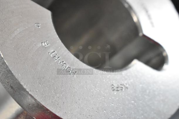 Close-up of a metal Hubart E M578 part with embossed text, showing fine surface texture.