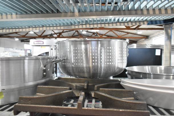 10 new kitchen items including 22" aluminum steamer and 16 qt. colander with handles, displayed on a metal shelf.