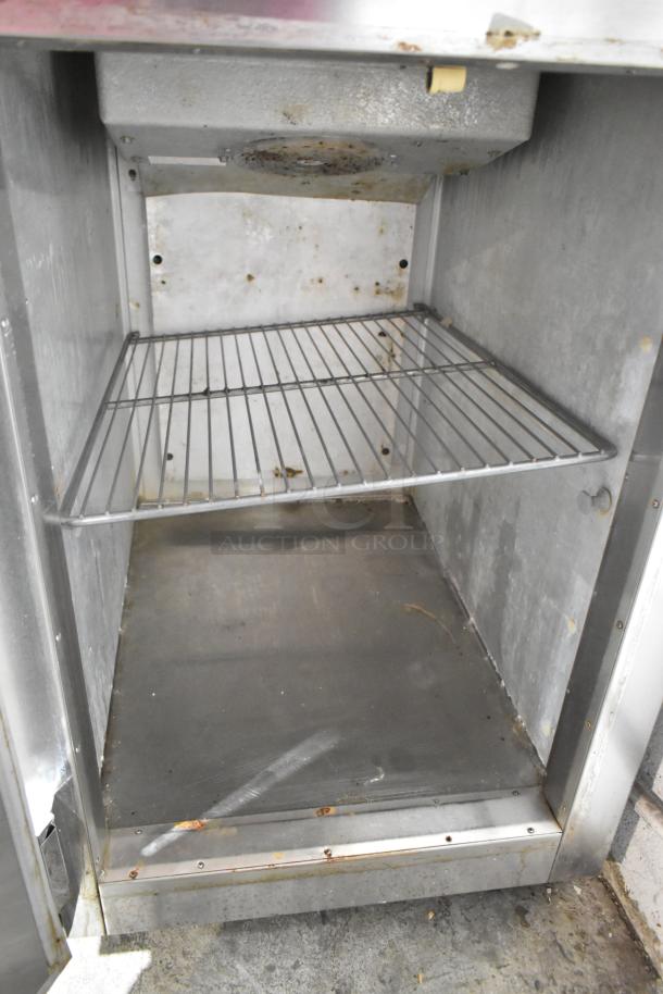 Traulsen ADT132KUT-HHS stainless steel commercial dual temp cooler and freezer, interior view, with rack, on casters.